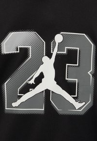 Schwarzes T-Shirt aus Stoff mit großen grauen und weißen grafischen Zahlen "23" und einer Silhouette eines Basketballspielers in einer Sprungpose.