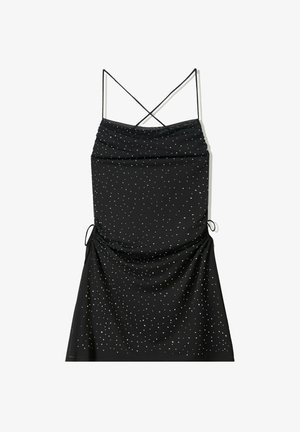Abito nero con sottili bretelle incrociate sulla schiena, texture arricciata e motivi di punti argento sparsi. Presenta lacci laterali per la regolazione.