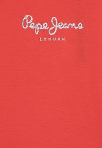 Pehmeästä puuvillakankaasta valmistettu punainen T-paita, jossa on etuosassa keskitetty kimaltava hopeinen logo "Pepe Jeans LONDON".