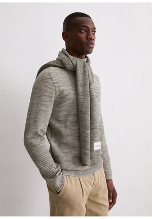 Grau gerippter Pullover mit einem passenden strukturierten Schal, der um den Hals drapiert ist. Kombiniert mit hellbraunen Cordhosen. Dezentes Markenlabel sichtbar.