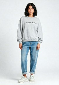 Felpa grigia con la scritta "HO PARLATO DI TE A CHATGPT", vestibilità rilassata, abbinata a jeans azzurri chiari e sneakers bianche. Outfit casual.