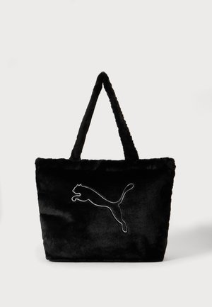 Sort taske i kunstpels med lange håndtag og stort hvidt Puma-logo med omrids midt på forsiden mod en ensfarvet baggrund.