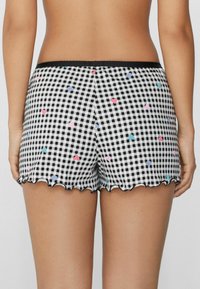 Zwart-witte gingham shorts met kleine kleurrijke hartpatronen. Golfrand en een elastische zwarte tailleband voor comfort.