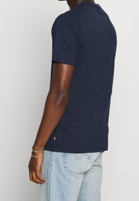 T-shirt in cotone blu navy con scollatura rotonda e maniche corte; presenta una piccola etichetta rossa sull'orlo e una vestibilità regolare.