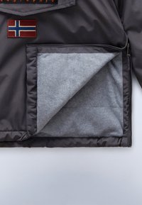 Veste sombre avec une doublure polaire grise visible partiellement dézippée, avec un patch du drapeau norvégien en haut à gauche.