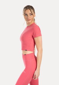 Rosa kort atletisk topp med korta ärmar, kombinerad med ljusrosa leggings med hög midja. Mjuk textur, tajt passform och minimal branding.