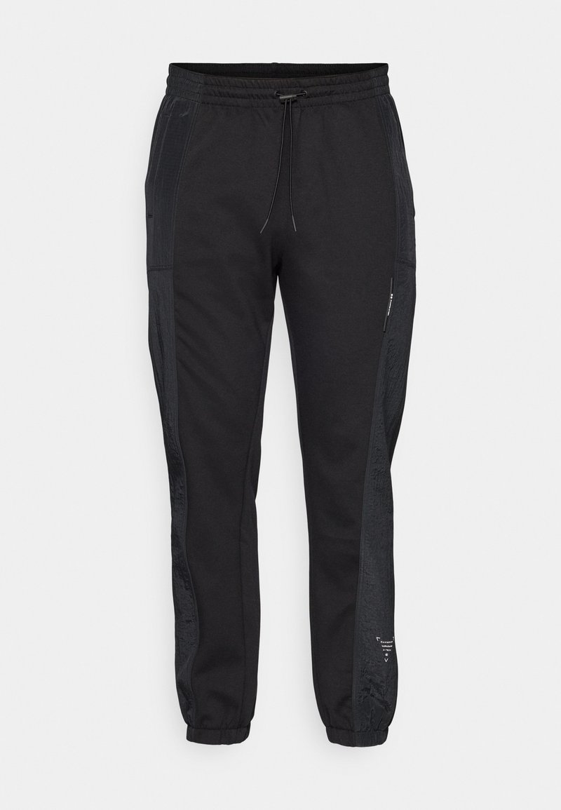 Pantalon de jogging noir avec taille élastique, cordon de serrage et poches latérales. Doté de panneaux latéraux texturés noirs et de poignets élastiques aux chevilles.