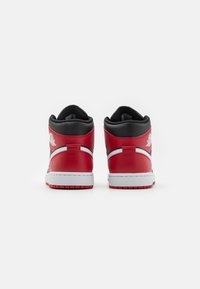 Wysokie trampki z czerwonej skóry, z czarnymi akcentami, białą podeszwą środkową i charakterystycznym logo na pięcie. Teksturowana powierzchnia i amortyzowany kołnierz.