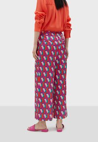 Färggranna byxor med vida ben som har ett geometriskt mönster i rosa, röd och blå. Tillverkade av ett lätt tyg med en jämn textur.