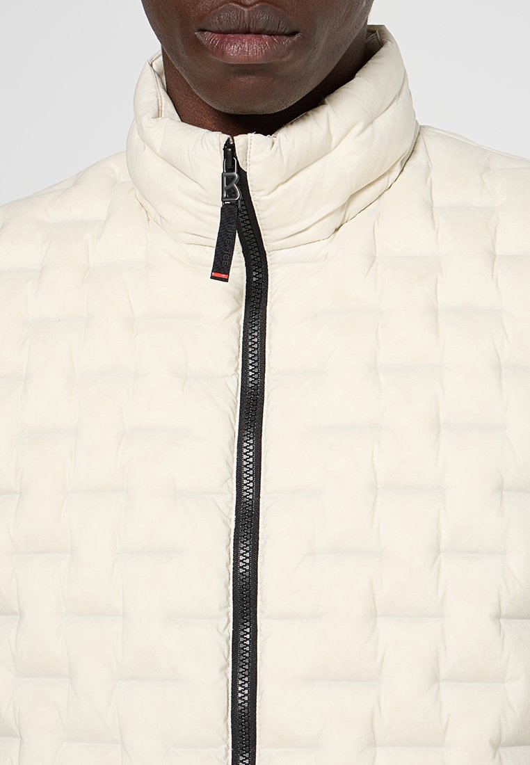 Weiße gesteppte Jacke mit Stehkragen und schwarzem Reißverschluss. Sie hat ein strukturiertes Muster und kontrastierende Reißverschlusselemente.