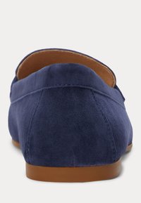 Sapatos slip-on de camurça azul-marinho com parte traseira arredondada, textura suave e sola de borracha castanha. Costura mínima e sem embellishments visíveis.