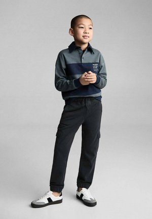Grau-blau gestreiftes Langarm-Polohemd mit Kragen, kombiniert mit schwarzen Cargo-Hosen und weißen Sneakers mit schwarzen Akzenten.