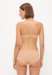 Beige strapless bra with a smooth texture, adjustable back closure, and matching beige high-waisted brief with seamless design.