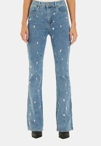 Jeans flare in denim blu con vari ornamenti in strass di colori come verde, blu e trasparente, con un classico design a cinque tasche.