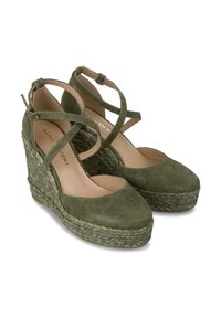 Zielone zamszowe sandały na koturnie z plecionką z juty, konstrukcja z krzyżującymi się paskami i zaokrąglonym czubkiem. Płaska podeszwa i zapięcie na klamrę przy kostce.