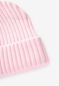 Rosa gestrickte Beanie-Mütze mit vertikaler Rippstruktur und umgeschlagenem Bündchen, aus weichem Material. Die Farbe ist gleichmäßig verteilt.