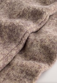 Tissu texturé marron et beige, présentant une surface douce et duveteuse avec une légère brillance. Le matériau semble épais et chaud, avec des motifs subtils.