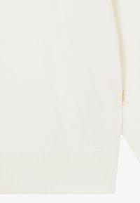 Maglione chiaro in morbido tessuto interlock. Presenta orli e polsini a costine, con una piccola etichetta del marchio cucita di lato. Tessuto liscio, design semplice.