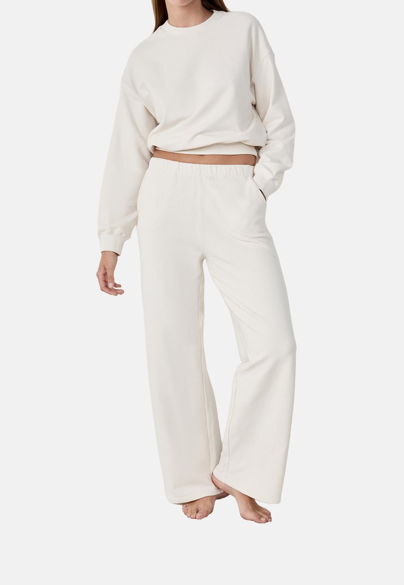 Krämlik, mjuk tyg loungewear-set som består av en kortad sweatshirt med långa ärmar och vida byxor med elastisk midja.