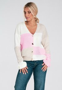 Sweter z dzianiny z dekoltem w serek, z różowymi, beżowymi i białymi ukośnymi paskami. Posiada guziki z przodu oraz ściągacze na mankietach.