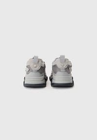 Gray athletic shoes featuring a mesh upper, suede accents, and a thick black sole with textured grooves and heel pull tabs.