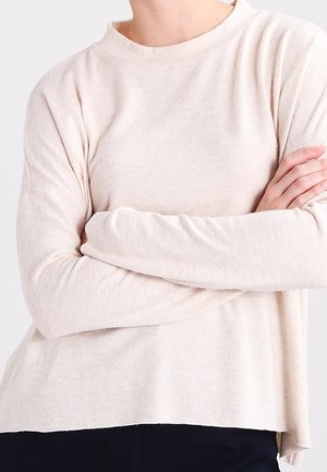 Pullover lungo beige chiaro a maniche lunghe con scollo alto, vestibilità ampia e texture morbida; presenta spalle scese e spacchi laterali all'orlo.