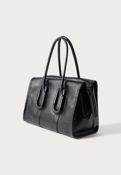 Sac à main en cuir noir avec deux poignées arrondies et coutures verticales, présenté sur fond blanc.