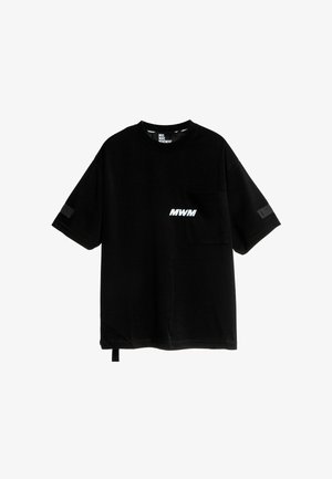 Camiseta de algodón negra con corte oversize, mangas cortas, bolsillo frontal, logo en blanco "MWM" y detalle de tela en la manga.