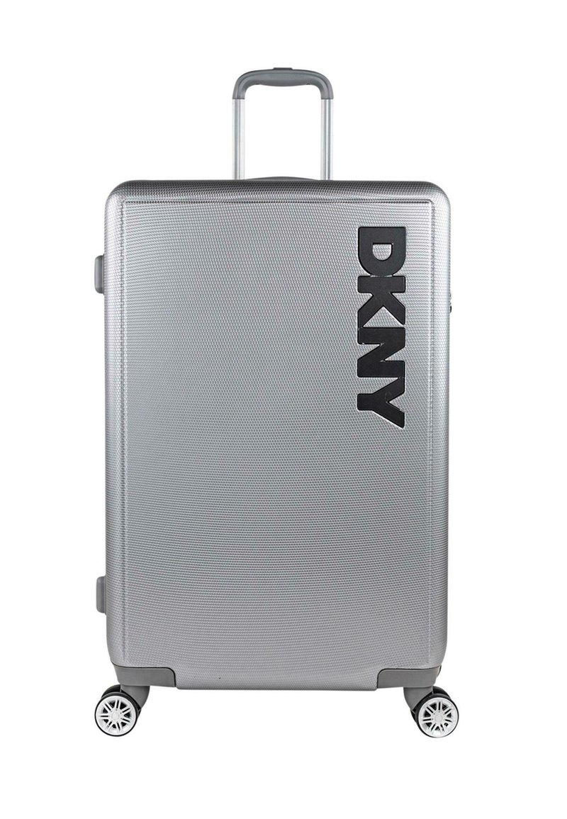 Maleta rígida plateada con superficie texturizada, que presenta un prominente logo negro de DKNY, un asa retráctil y cuatro ruedas multidireccionales.