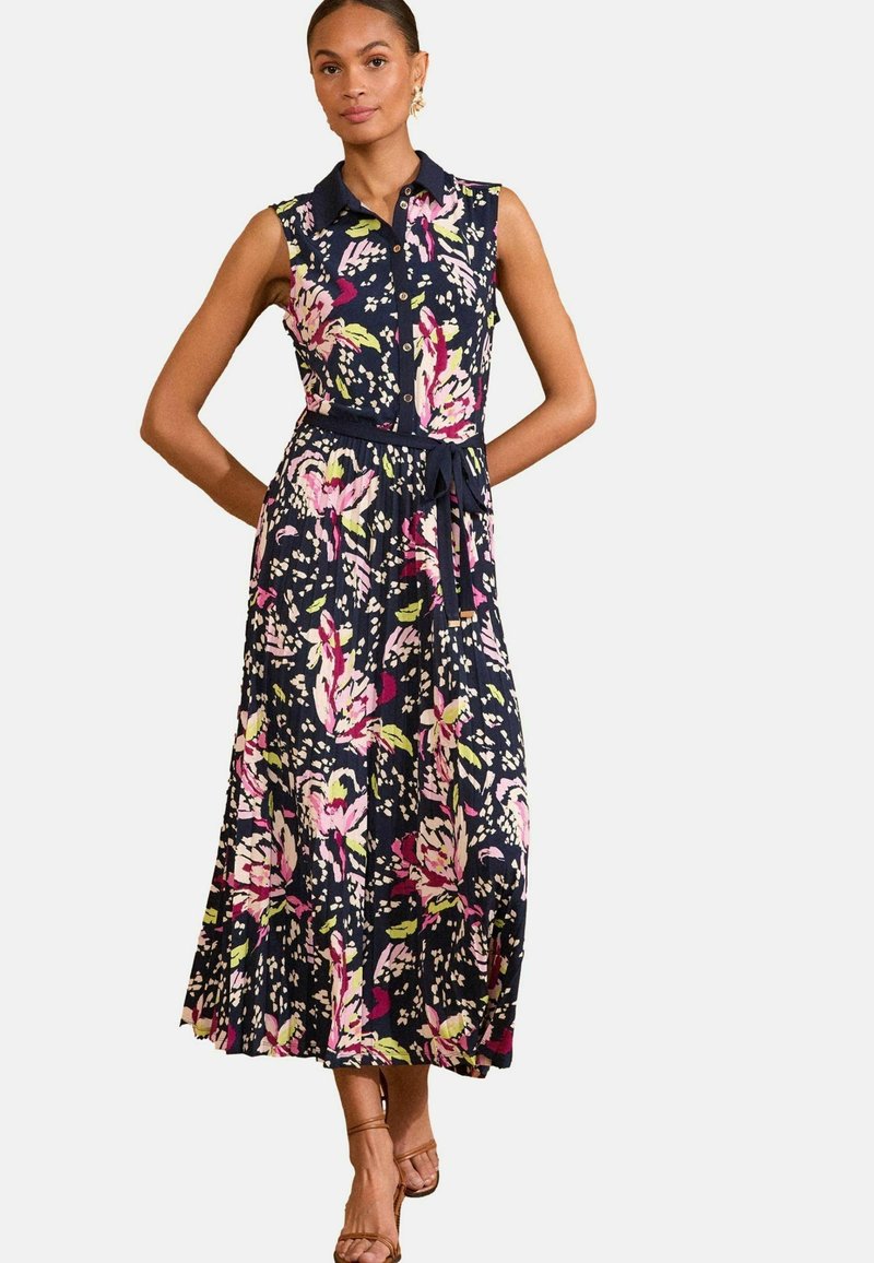 Temno modra cvetna obleka s ovratnikom, brez rokavov in pasom. Ima rožnate in zelene vzorce na tekočem materialu.