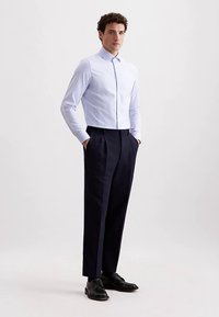 Lichtblauw gestreept overhemd met knopen en kraag, gecombineerd met donkerblauwe geplooide broek en zwarte schoenen, voor een formele uitstraling.