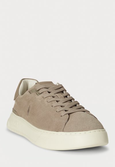 Sneaker din suede bej, cu vârful rotunjit, suprafață texturată și talpă din cauciuc alb. Dispune de șireturi asortate și un design minimalist.