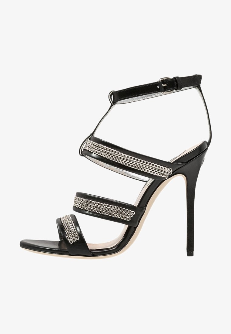 Sandale à talons hauts noire avec trois brides ornées de chaînes et une fermeture à boucle à la cheville.