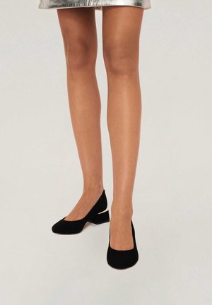 Czarne zamszowe buty na szerokim obcasie z ostrym noskiem, z małym złotym akcentem z tyłu. Gładka tekstura, elegancka sylwetka.