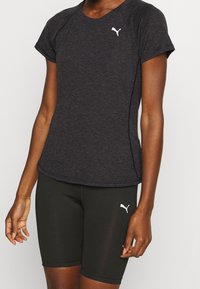 Svart idrottströja med korta ärmar och rundad halsringning, prydd med en vit logotyp. Kombineras med svarta åtsittande shorts med logodetaljer.