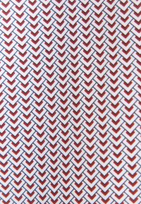 Tessuto con un motivo ripetuto di forme a chevron rosse e blu su sfondo bianco, con una finitura tessile strutturata.