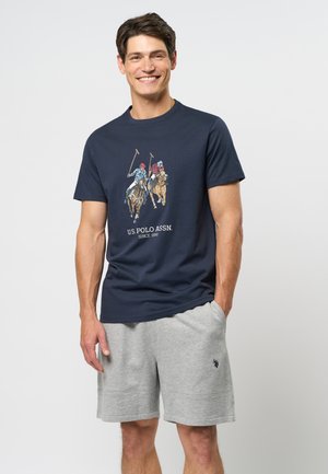 Tricou bleumarin cu un grafic de meci de polo în mai multe culori, având textul "U.S. POLO ASSN. DIN 1890." Combinat cu pantaloni scurți gri, din țesătură texturată.