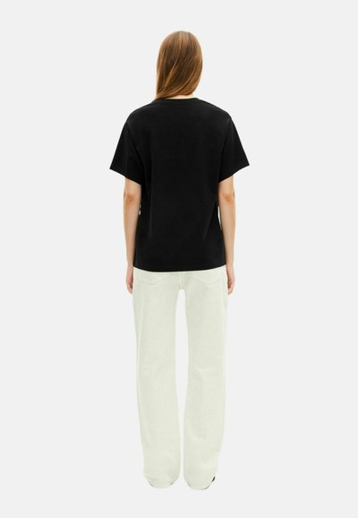 Svart bomull T-skjorte med avslappet passform, korte ermer og rund hals, kombinert med lyse, vide bukser.