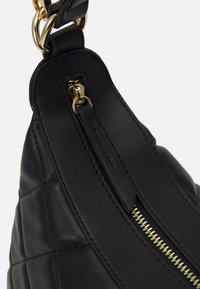Black leather bag featuring a quilted design, gold hardware, and a zipper closure. The strap is also leather with gold accents.