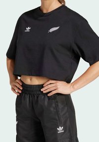 Svart kortärmad t-shirt med vita Adidas- och fern-loggor. Matchad med svarta shorts med dragsko.