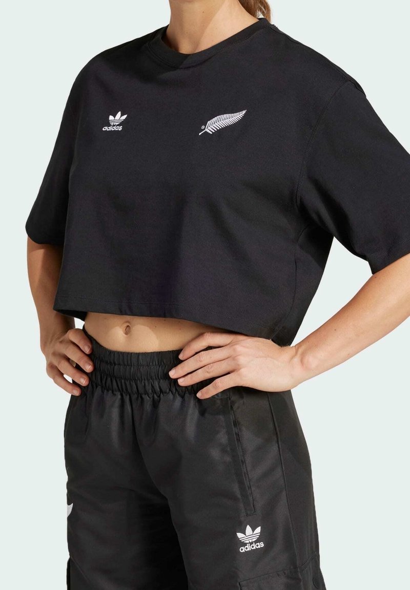 Svart kortärmad t-shirt med vita Adidas- och fern-loggor. Matchad med svarta shorts med dragsko.