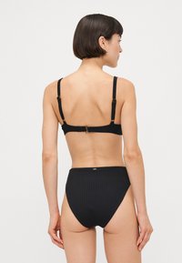 Schwarzes, geripptes Bikini-Set mit verstellbaren Trägern und goldenen Hardware-Details; verfügt über einen hochgeschnittenen Hosenboden und strukturierter Stoff.