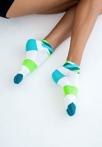 Bunte Socken mit einer Mischung aus Weiß, Türkis und Grün sowie einem geometrischen Muster. Die Zehenkappen sind in Dunkeltürkis.
