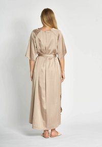 Langes, beiges Satin-Kleid mit lockerer Passform, weiten Ärmeln und einer gebundenen Taille. Verfügt über einen Rückenschlitz für zusätzliche Textur und Bewegung.