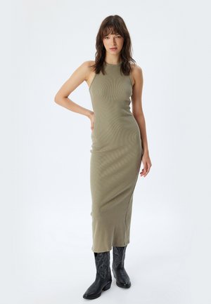 Olive green, prążkowana, bezrękawnikowa sukienka maxi o dopasowanej sylwetce, z bocznym rozcięciem, w połączeniu z czarnymi, haftowanymi botkami do kostki.