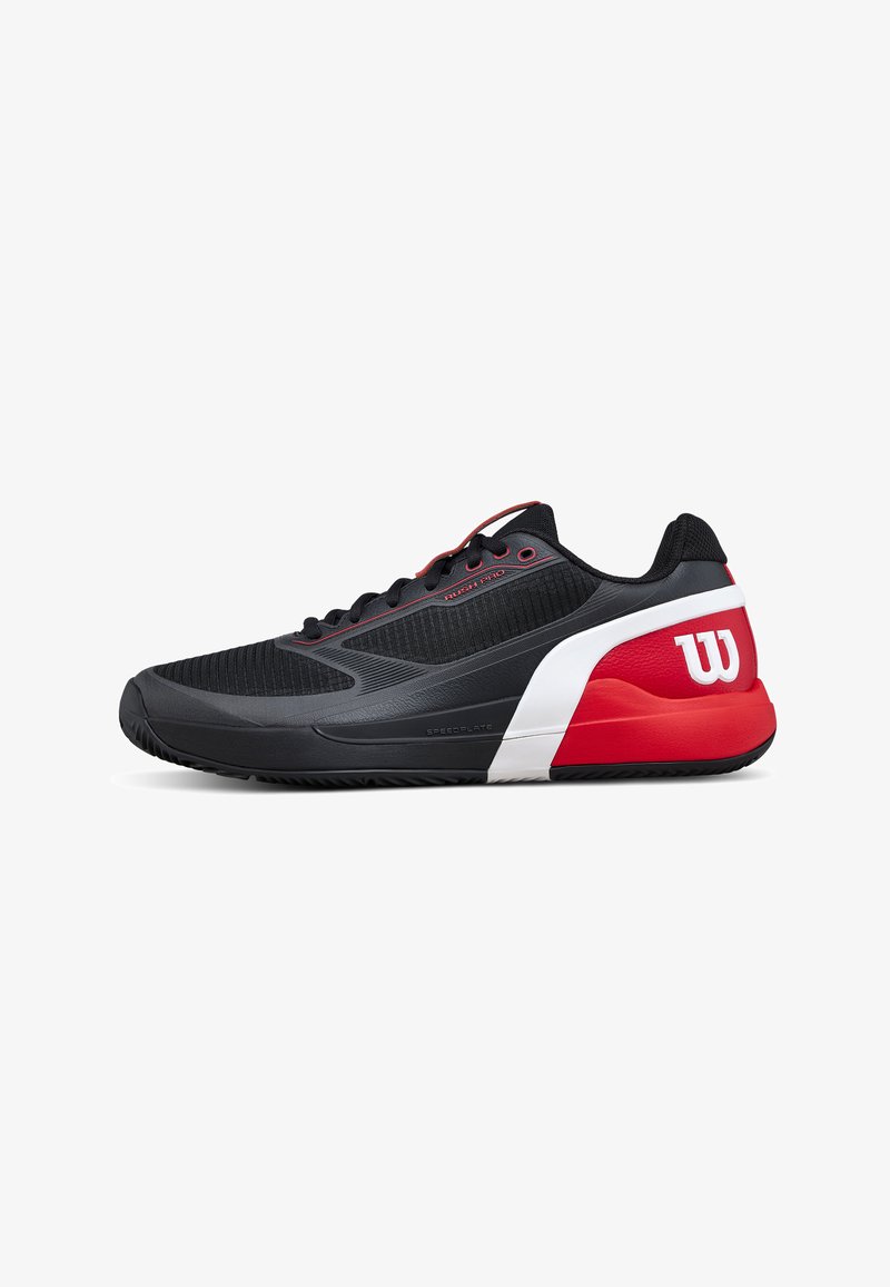 Chaussure de sport basse noire, rouge et blanche avec lacets à l'avant, semelle texturée et logo de la marque Wilson sur le talon.