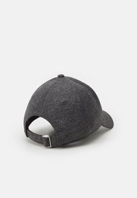 Grå texturerad basebollcap med en böjd skärm, justerbart band bak och ventilationshål på sidorna.