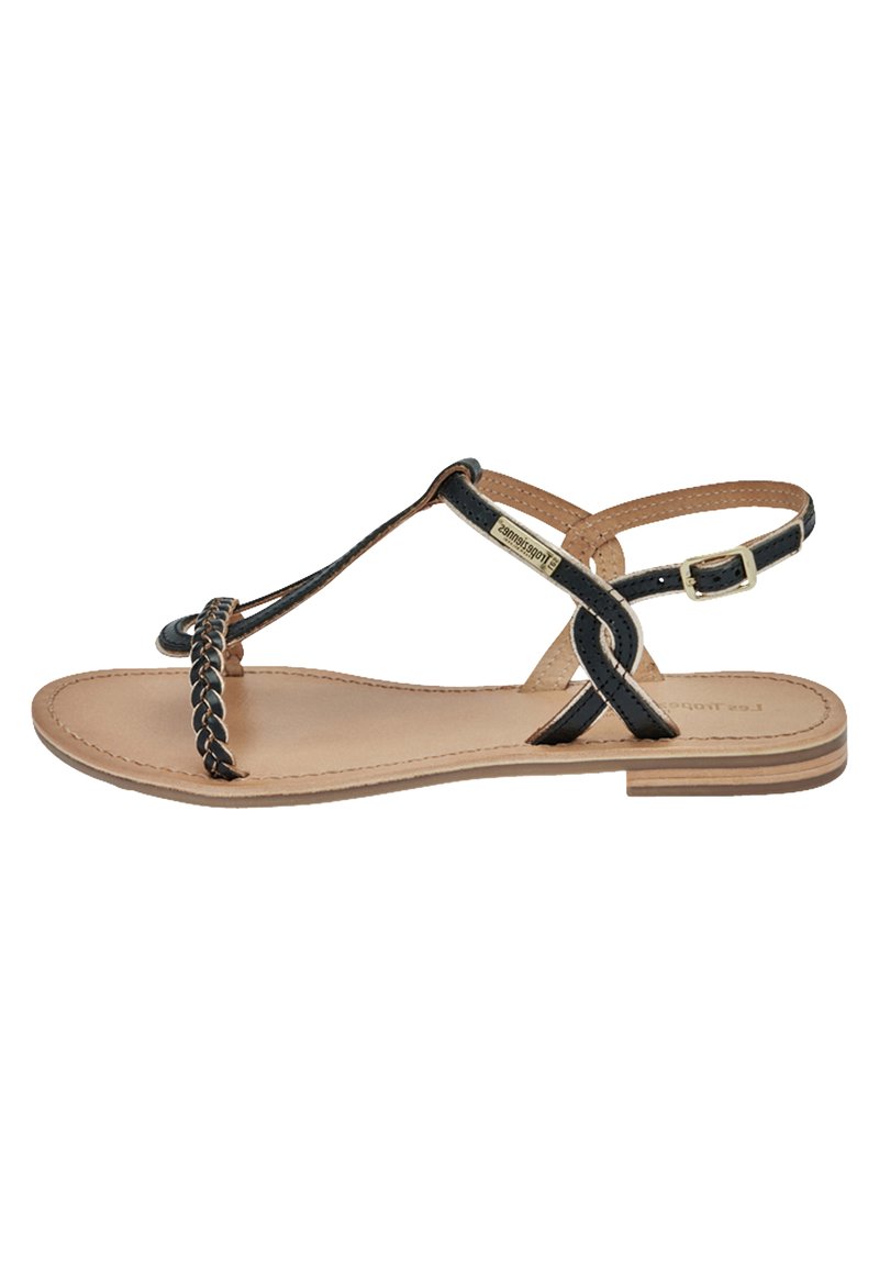 Sandal a strappo intrecciato nero con suola color cammello, caratterizzata da un design piatto, cinturino alla caviglia regolabile e dettagli minimalisti.