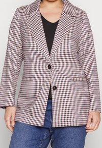 Rutig kavaj i röd, blå och vit, med en notch krage, två framfickor och en enkel knappstängning. Tillverkad av en bomullsblandning.