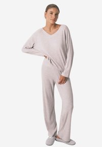 Lys grå loungewear sæt bestående af en V-hals langærmet top og matchende brede bukser, lavet af blødt, struktureret stof.